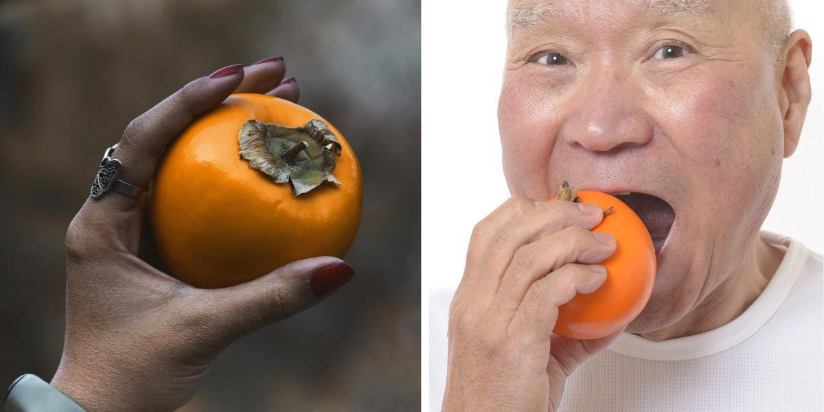 En kvinnas hand håller i en persimon och en man äter en persimon