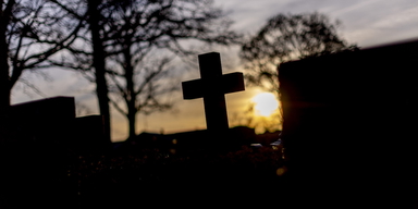 En gravsten i form av ett kors på kyrkogård. Tiden mellan dödsfall och begravning fortsätter att öka, trots lagändringen 2012 som skulle minska tiden