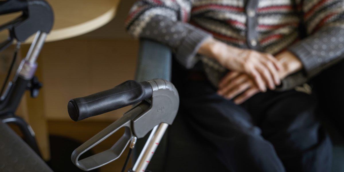 En person på ett äldreboende sitter i en stol med sin rullator bredvid sig. Livet på äldreboende innebär ofta stillasittande, något som forskning gång på gång visat inte är bra för hälsan. Även äldre människor behöver röra på sig och det finns både enkla och billiga sätt att ändra rutinerna på boenden för att införa mer fysisk aktivitet.