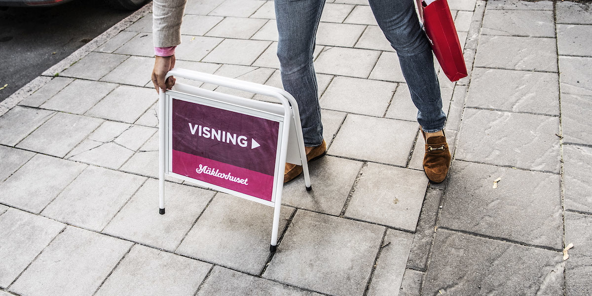 Bostadsvisning. En mäklare från Mäklarhuset har satt ut en skylt utanför en bostadsrätt som är till salu. Den ena av mäklarbröderna som lurade 87-åriga Karin att sälja sin tvåa på Kungsholmen för två miljoner mindre än den var värd jobbade på Mäklarhuset i Stockholm, det hela uppdagades och stoppades tack vare att en granne larmade.