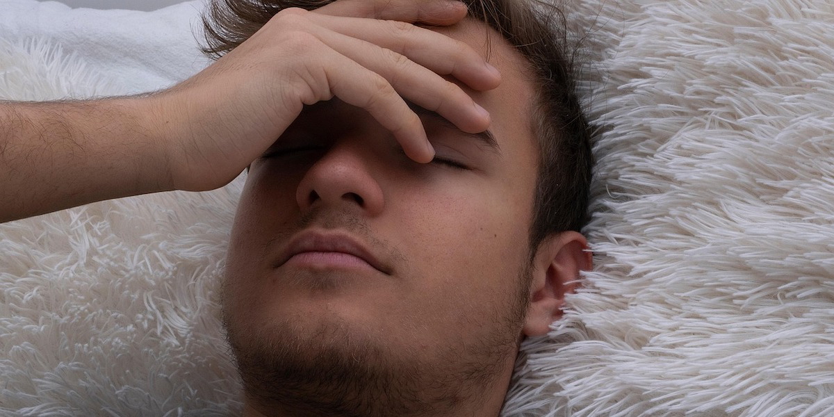 En ung man känner sig sjuk. Enligt en rapport har personer under 30 dubbelt så mycket korttidsfrånvaro som sina äldre kollegor.