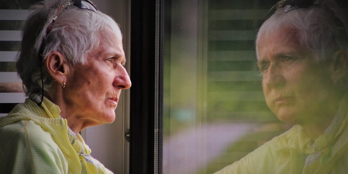 En kvinna tittar ut genom ett fönster. Många 65-plussare vill flytta till ett boende som passar bättre men gör det inte eftersom de tycker att flytten är för krånglig.