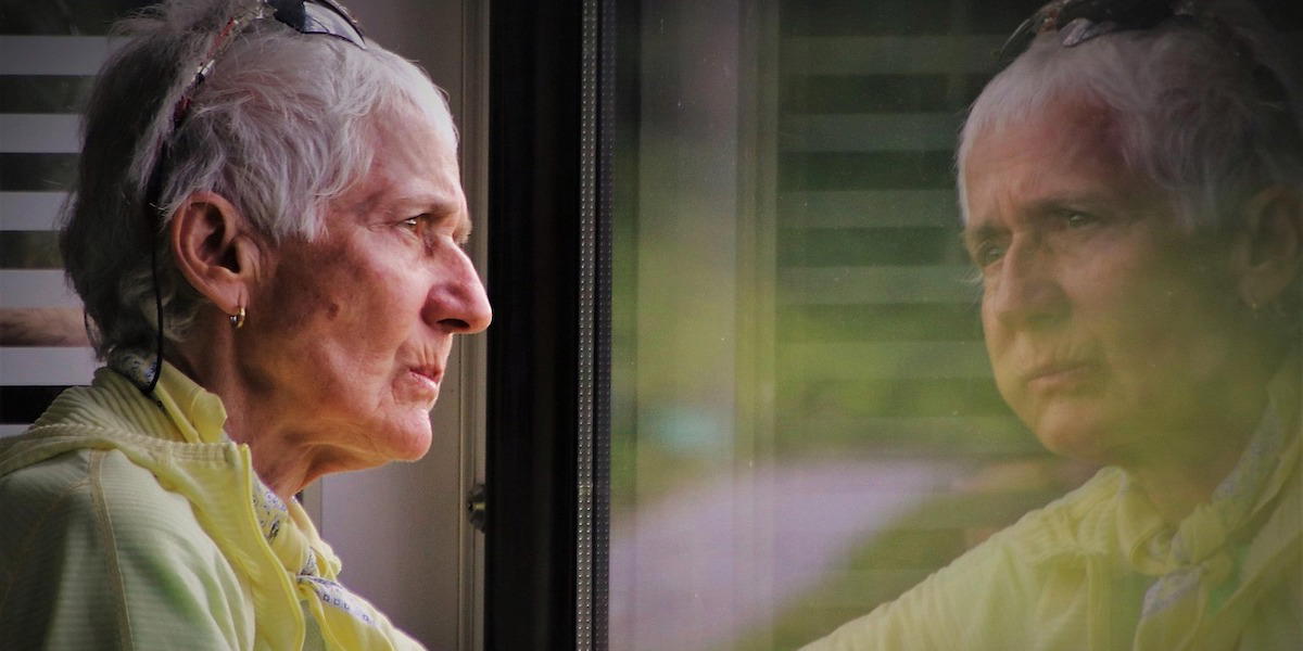 En kvinna tittar ut genom ett fönster. Många 65-plussare vill flytta till ett boende som passar bättre men gör det inte eftersom de tycker att flytten är för krånglig.