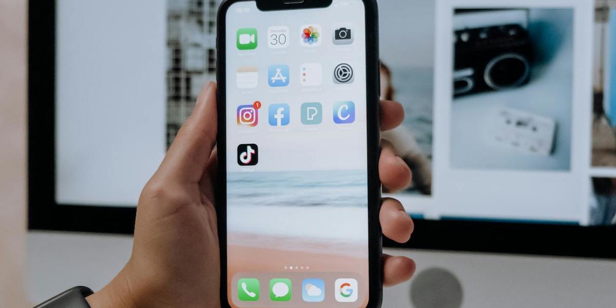 Någon håller upp en mobil framför en datorskärm. Allt fler tar hjälp av resegrupper på Facebook för att planera sin semesterresa, här är några tips för hur du hittar rätt personer i grupperna