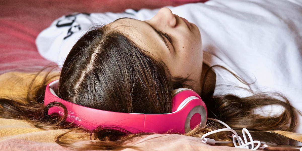 En flicka sover med rosa hörlurar. Enligt en ny studie kan rosa brus, som allt oftare används i appar och ljudmaskiner för att hjälpa människor att somna i stället kan försämra sömnkvaliteten.