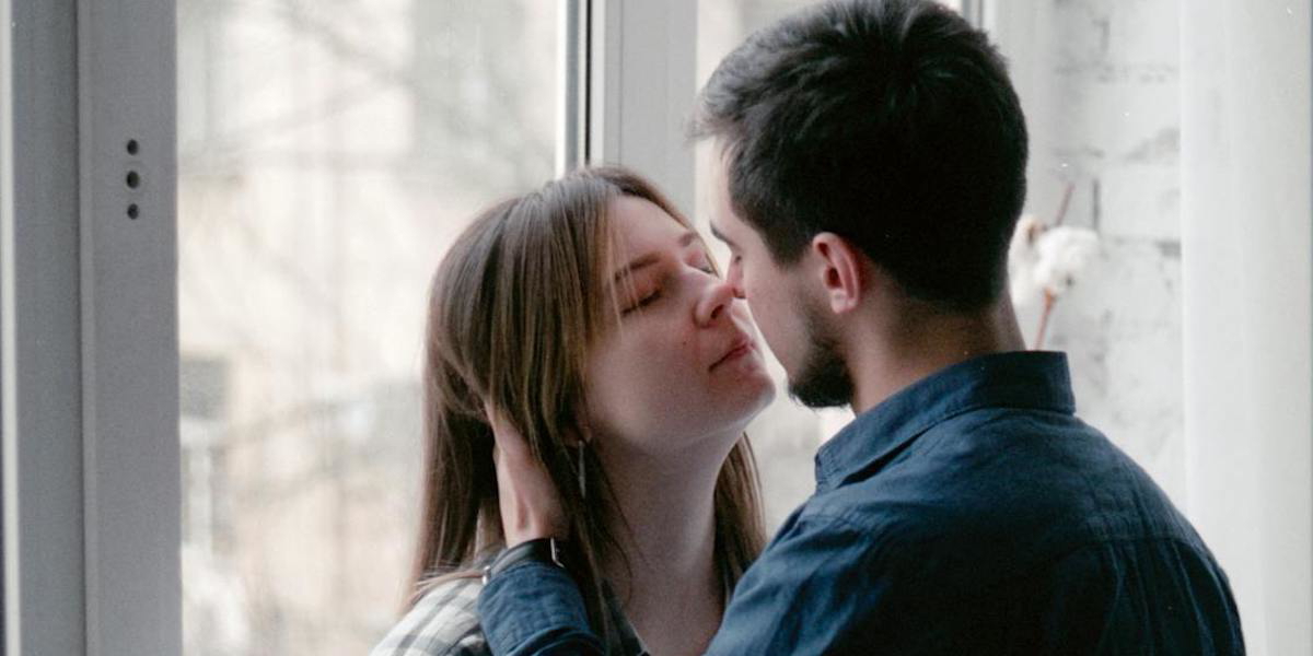 Ett ungt par framför ett fönster. Enligt en studie lever män i parrelationer i genomsnitt fem år längre om de gör det här på morgonen.