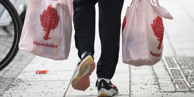 En man bär hem livsmedel i två matkassar från Hemköp. Den första april ska sänkt matmoms ge billigare mat, men frågan är hur mycket billigare den kommer bli när det geopolitiska läget pressar upp priserna.