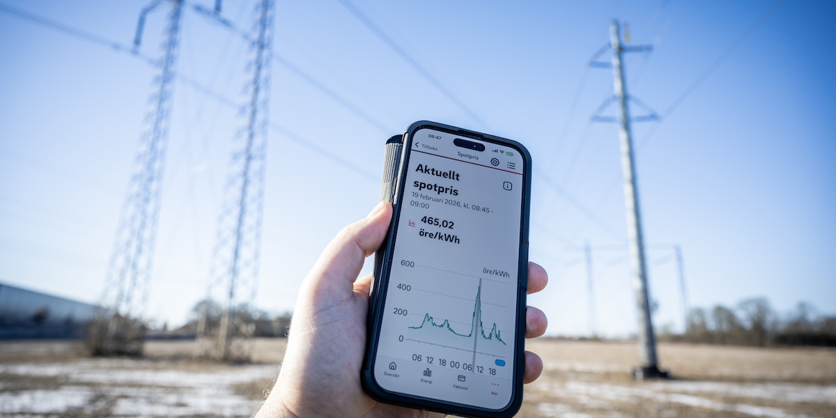 Klarblå himmel och vindstilla bakom högspänningsledningar och en mobil visar elpriset i elområde 4 på över fem kronor per kilowattimme.