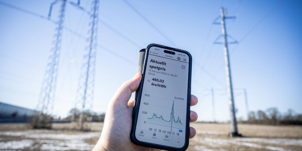 Klarblå himmel och vindstilla bakom högspänningsledningar och en mobil visar elpriset i elområde 4 på över fem kronor per kilowattimme.