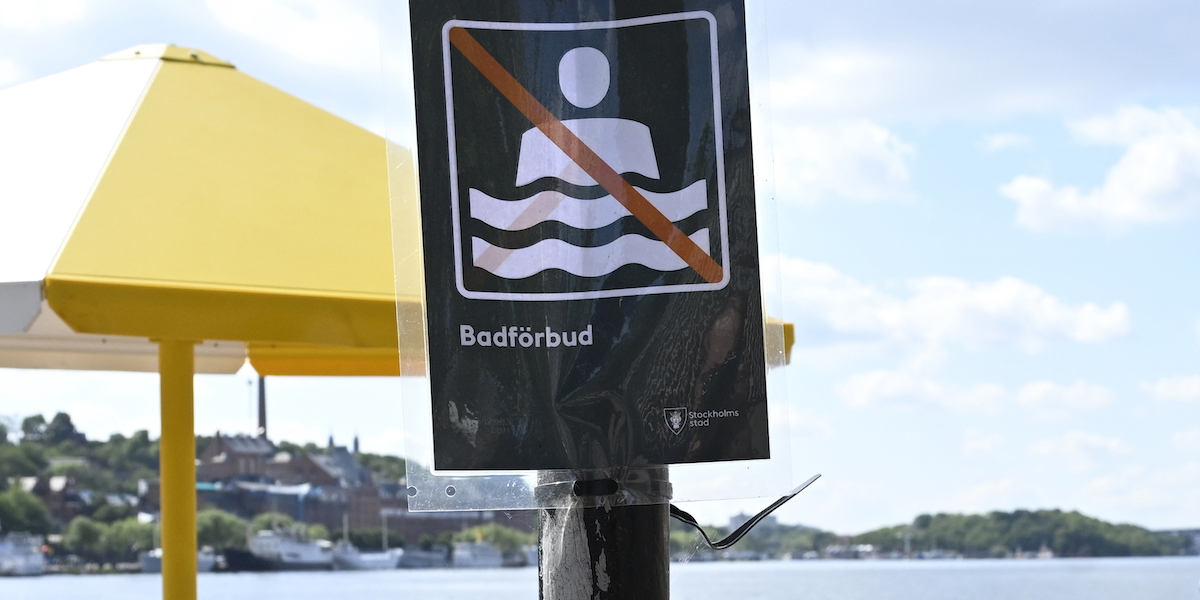 En skylt informerar om badförbud vid en kaj på Riddarholmen. Badförbud har införts på populär strand i Málaga.