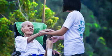 En äldre japansk kvinna i rullstor får hjälp av en vårdare. Svenskar och japaner över 75 är lika friska men bättre äldrevård i Japan gör att de lever längre