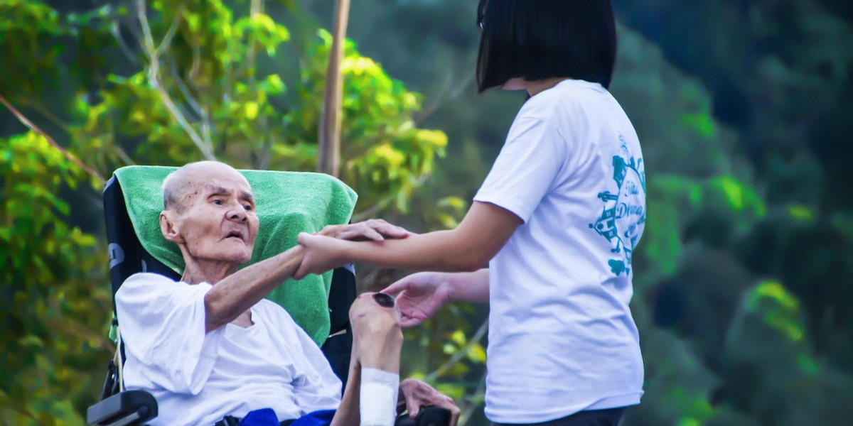 En äldre japansk kvinna i rullstor får hjälp av en vårdare. Svenskar och japaner över 75 är lika friska men bättre äldrevård i Japan gör att de lever längre