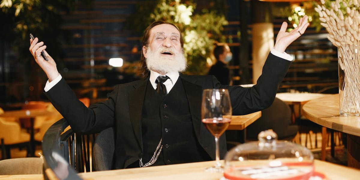 En äldre man är glad på en restaurang. En ny undersökning visar att fler pensionärer vill använda upp sina pengar än lämna dem i arv till barn och barnbarn.