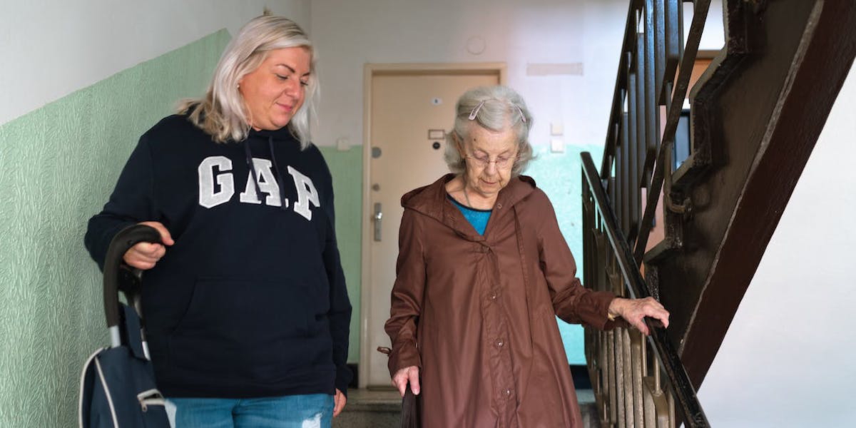 En kvinna hjälper en äldre kvinna. Kristdemokraterna vill att rätten till lediga dagar för vård av förälder utreds så att vuxna barn kan hjälpa sina äldre föräldrar vid exempelvis vårdbesök, plötslig sjukdom eller praktiska situationer vid livskriser.