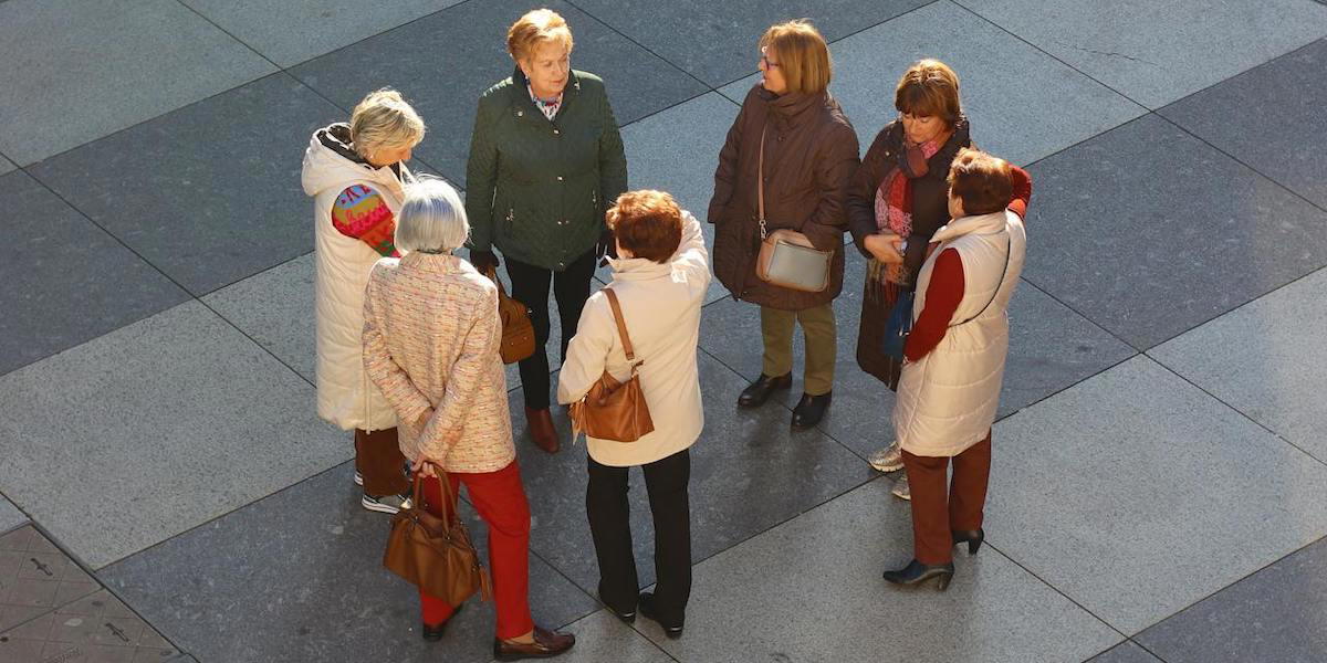 En grupp äldre står i en cirkel och pratar.