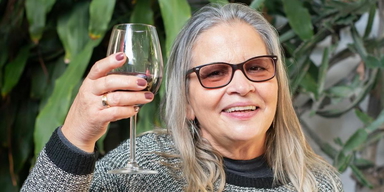 En kvinna skålar med ett glas vin. Alkohol kan påverka både klimakteriebesvär och pollenallergi genom att förvärra symtomen, här får du veta varför.