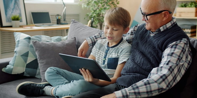 En pensionär och ett barn tittar på en skärm.