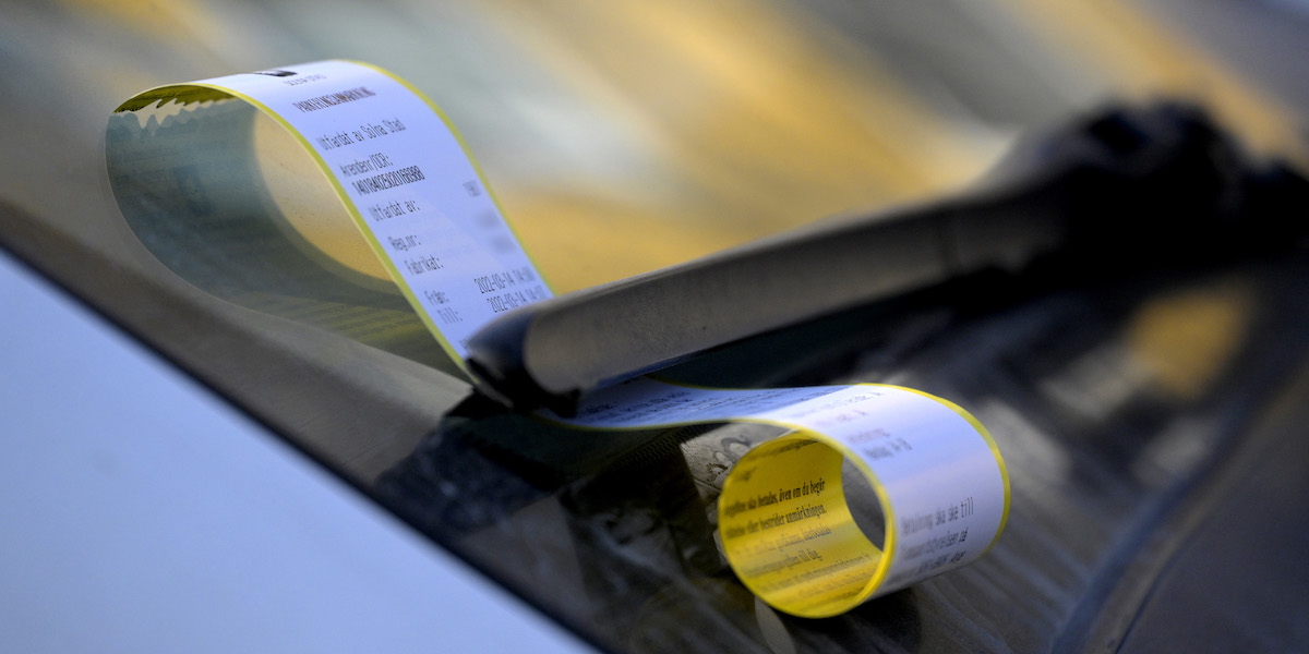 Felparkerad bil med en P-bot fastklämd under vindrutetorkaren. Han har ett giltigt parkeringstillstånd för rörelsehindrade men när han parkerade på en handikapplats fick han böter eftersom tillståndet inte syns på parkeringsvaktens dokumentationsfoto.