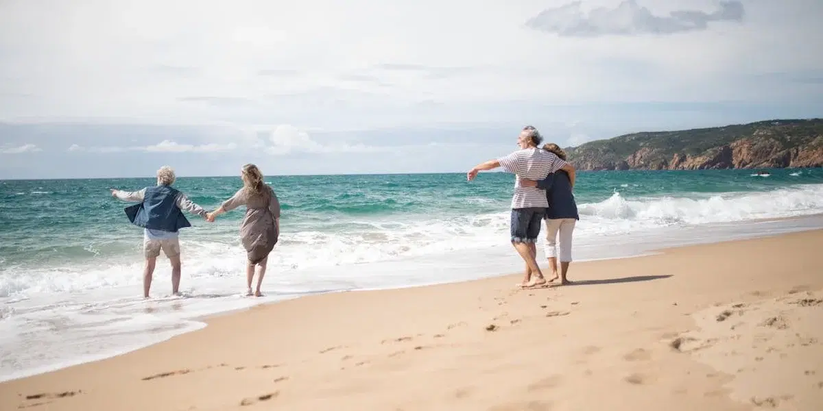 Två par på en sandstrand. En ny undersökning har tagit reda på hur mycket svenska hushåll planerar att spendera på resor och andra större aktiviteter i sommar, samt vad som oroar mest inför sommarsemestern.