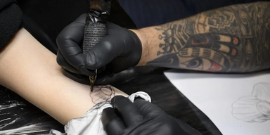 En tatuerare tatuerar in en pärla på en arm. Det har blivit allt mer populärt att tatuera sig, men forskning visar att tatueringar kan öka risken för cancer.