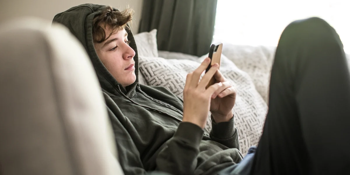 En pojke sitter hemma och tittar på sin mobiltelefon. Allt fler föräldrar oroar sig för och hör av sig om barn som inte klarar skolnärvaro. Det visar en ny genomgång av samtalen till Familjehjälpen och Bris.