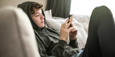 En pojke sitter hemma och tittar på sin mobiltelefon. Allt fler föräldrar oroar sig för och hör av sig om barn som inte klarar skolnärvaro. Det visar en ny genomgång av samtalen till Familjehjälpen och Bris.