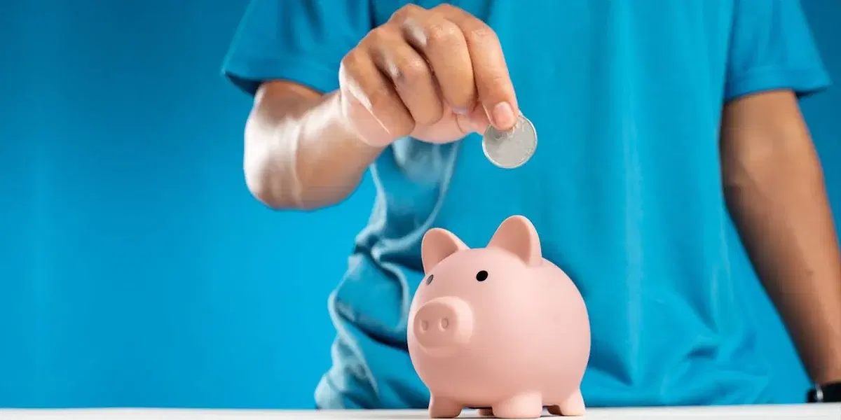 en man lägger ett mynt i en spargris. Nästan en tredjedel av svenskarna känner sig enligt en ny undersökning otrygga med sitt pensionssparande.