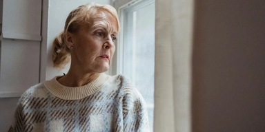 En kvinna tuttar ut genom ett fönster. Pensionärsorganisationer i Linköping vill motverka ensamhet bland äldre och anordnar ett seniorläger för personer från 65 år och uppåt.