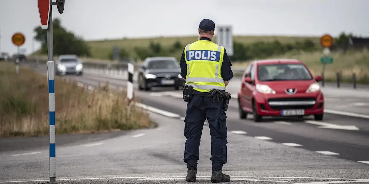 En polis står vid en väg med bilar.