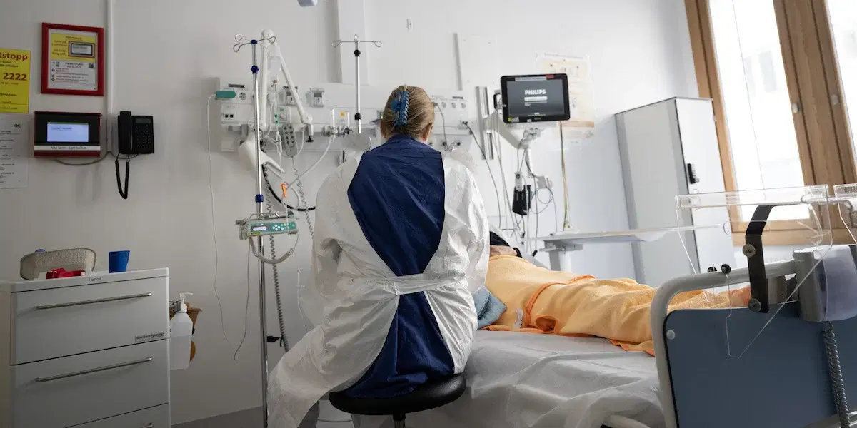 en sjuksköterska vid en patients sjuksäng på ett sjukhus. Sverige har byggt ett system som är bra på att behandla sjukdom, men sämre på att hjälpa människor att förbli friska.