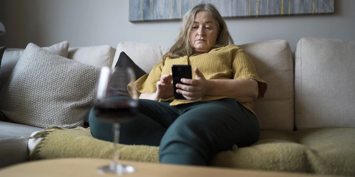 En kvinna sitter själv med mobilen och ett glas vin. Svenskar umgås mindre med vänner i dag än de gjorde för 30 år sedan, det är också färre svenskar som tycker att det är viktigt med sann vänskap och kärlek.
