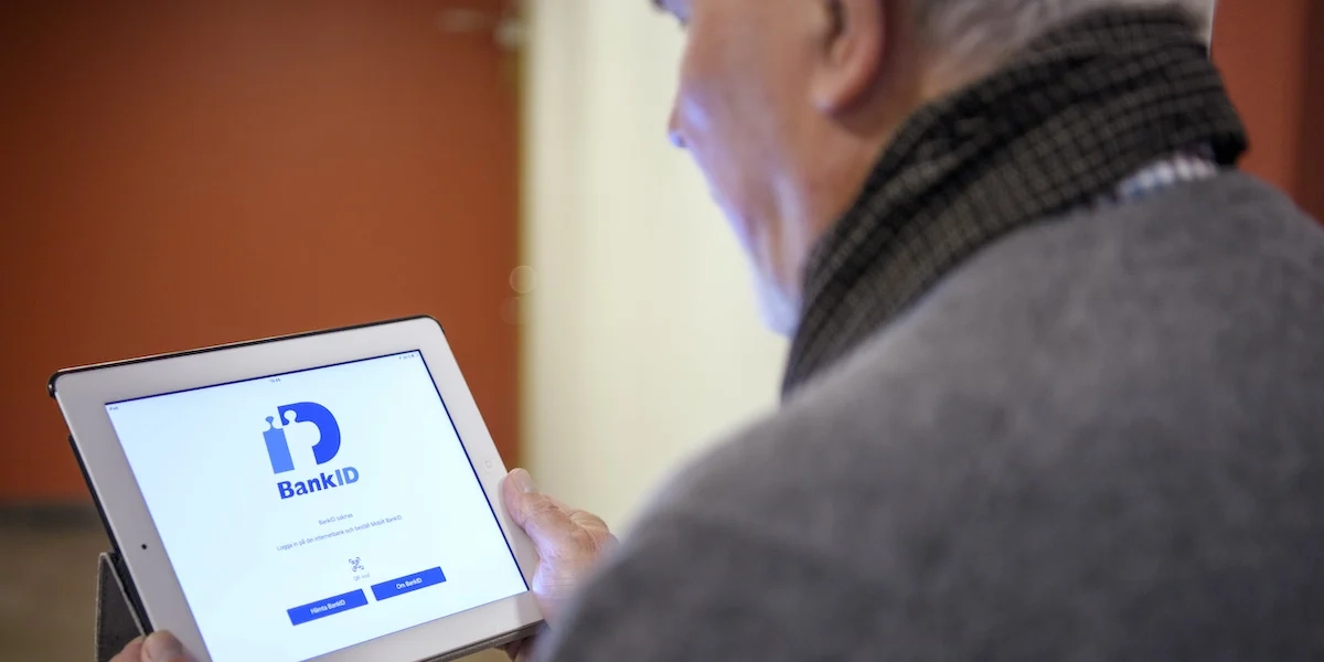 En man håller i en surfplatta med bank-id. Ett bedrägeri börjar ofta med att en okänd person tar kontakt och slutar med en banköverföring, och skyddet för den som har blivit lurad av en bedragare att använda sitt bank-id har varit svagt.