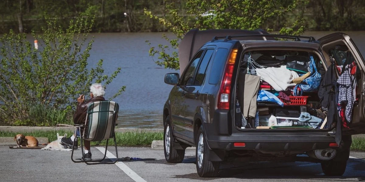 En man och två hundar vilar på en parkeringsplats med en fullpackad bil. Det är allt fler svenskar som ger sig ut på bilresa, men det är många som packar bilen för tungt eller kör för långa sträckor utan paus.