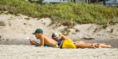 Ett par ligger på en strand. Även många av de akademiker som inte upplever att de förväntas vara tillgängliga för jobbet under semestern är det, men om chefen ringer och ber dig avbryta din semester, oavsett om det gäller en timme eller en dag, är det viktigt att ni kommer överens om ersättningen.