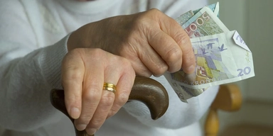 En äldre kvinna med käpp håller i sedlar. Är du pensionär? Här är sex sätt att spendera dina besparingar utan skuldkänslor.