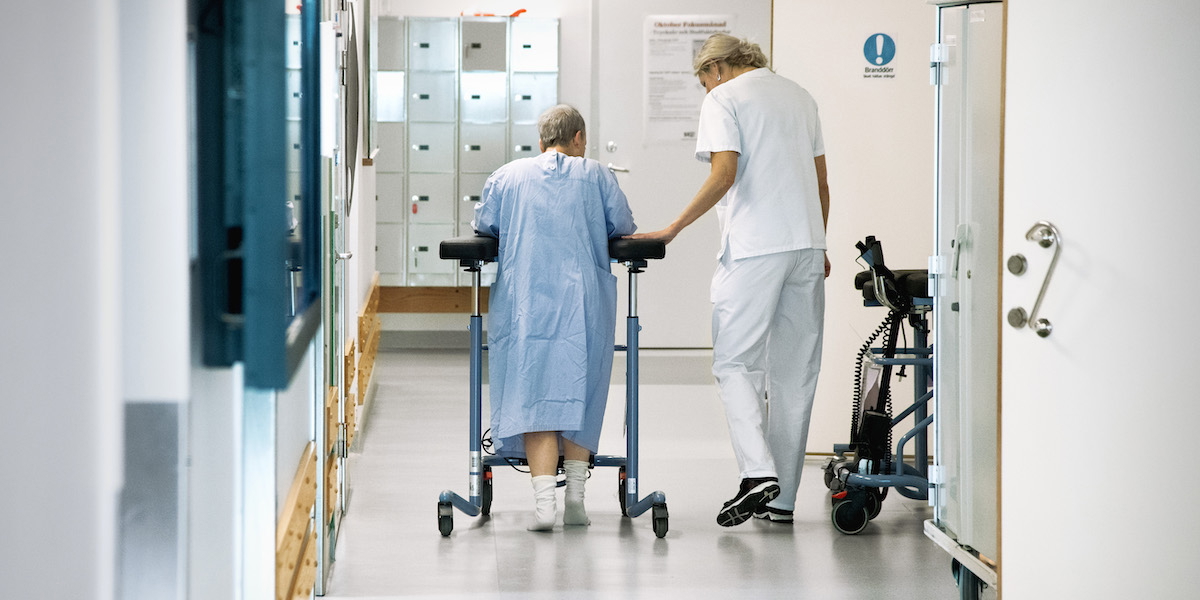 En vårdare och en patient i en sjukhuskorridor. Regionerna går med minus i år och även framöver beräknas deras resultat bli svagt, vilket påverkar vården negativt