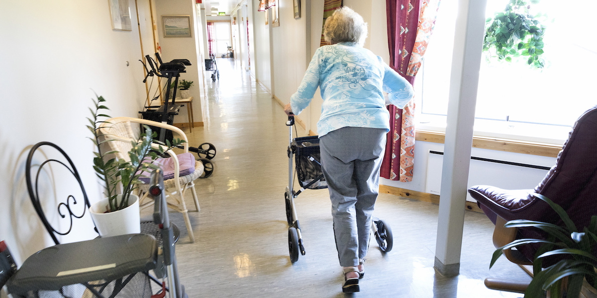 En äldre dam med rullator går i en korridor. Enligt en ny rapport från Socialstyrelsen måste arbetsmiljön inom äldreomsorgen bli bättre för att personalen ska vilja jobba kvar.