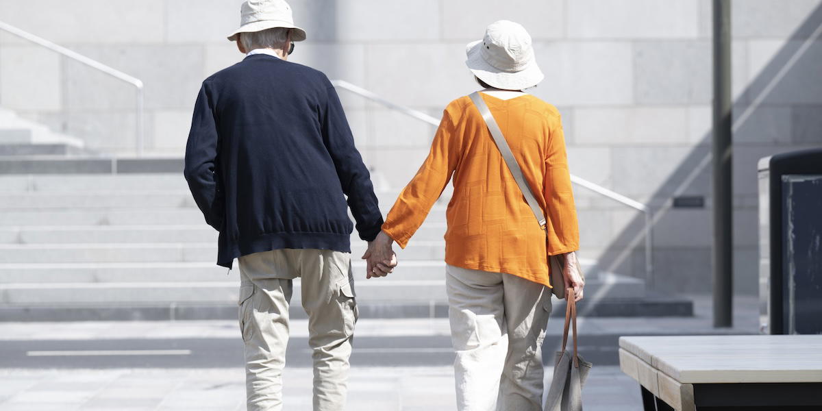 Två stiliga pensionärer går hand i hand runt på slussen i Stockholm.